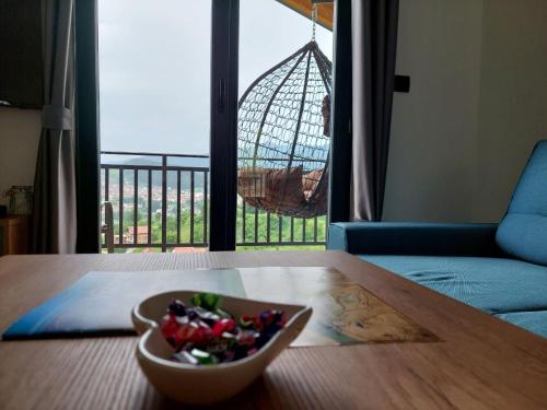 a bowl of fruit on a wooden table with a swing at Apartmani Višegradski pogled in Višegrad