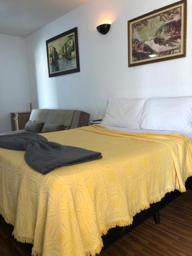 a bedroom with a bed with a yellow blanket on it at Palladium Apart Service in São Vicente