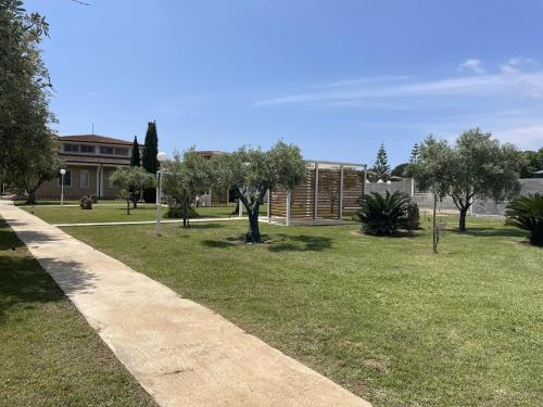 a park with a building and trees and a sidewalk at Verter Home Resort in Ovile la Marina