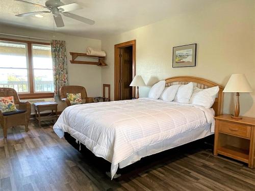 a bedroom with a large white bed and a chair at Pony Island Inn in Ocracoke