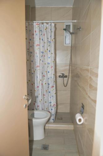 a bathroom with a toilet and a shower curtain at Prado Hotel Apartments in Limín Litochórou