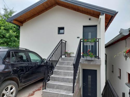 a car parked in front of a house with stairs at Apartmani Višegradski pogled in Višegrad