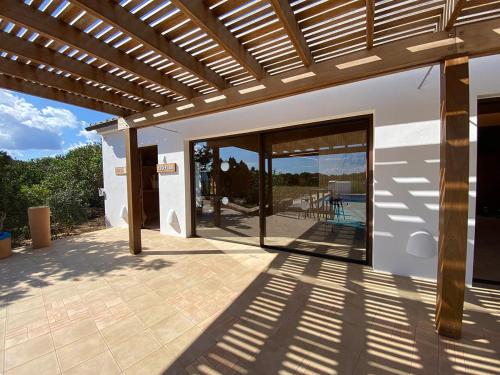 a patio with a wooden pergola with a view of a house at Punta Rasa Formentera Apartments in Cala Saona