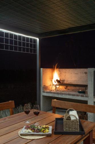 a table with two glasses of wine and a fireplace at Casa de Uco Vineyards and Wine Resort in Los Árboles