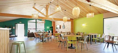 un restaurante con mesas, sillas y paredes verdes en Huttopia Etang Fouché, en Arnay-le-Duc