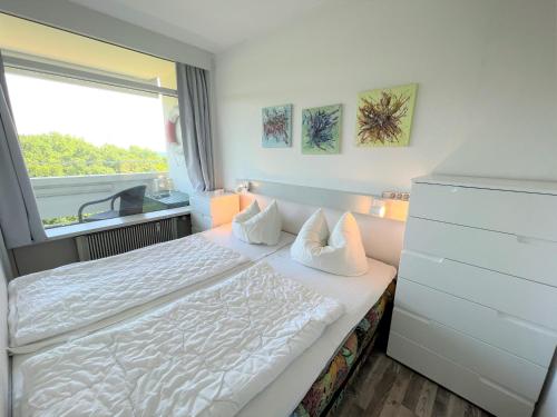 um quarto com uma cama branca e uma janela em Panoramic App A05-2 em Sierksdorf