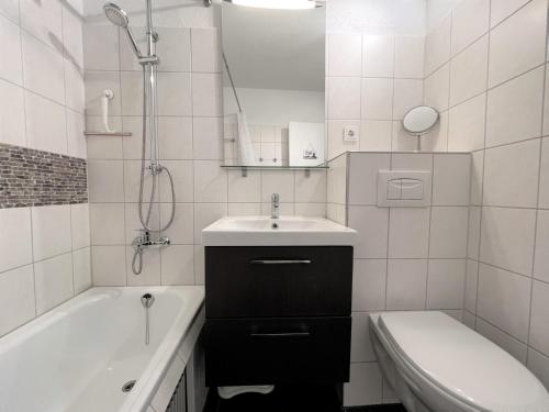 a white bathroom with a sink and a tub and a toilet at Panoramic App A03-1 in Sierksdorf