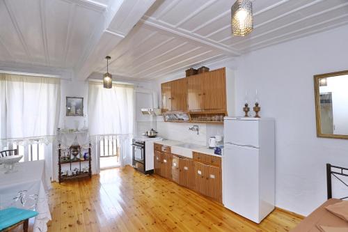 een keuken met een witte koelkast en houten kasten bij House of town in Skopelos Town
