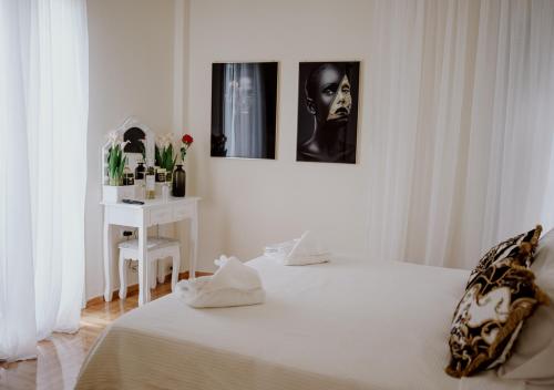 a white bedroom with a bed and a table at ROH Suites in Athens