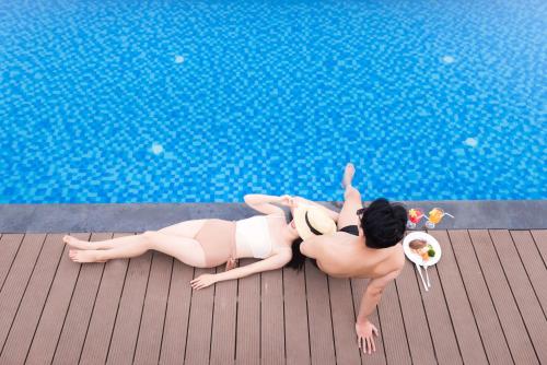 a couple of women laying next to a swimming pool at Minh Chau Pearl Hotel & Spa - Quan Lan Island in Quang Ninh