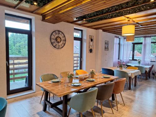 a dining room with a table and chairs and a clock at Vila PANORAMIC Busteni in Buşteni