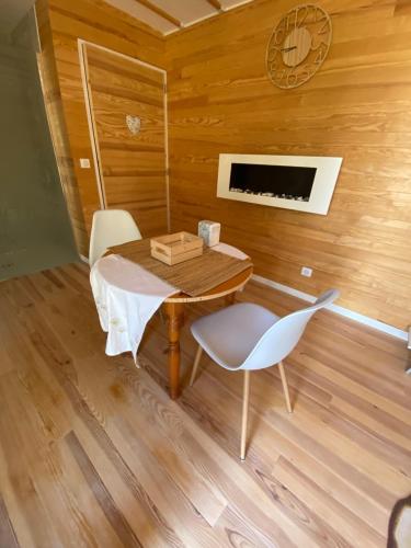 una mesa y sillas en una habitación con paredes de madera en L'écolodge de Laeti, en Lunéville
