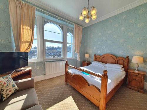a bedroom with a bed and a tv and a couch at The Purple Tree Guest House in Torquay