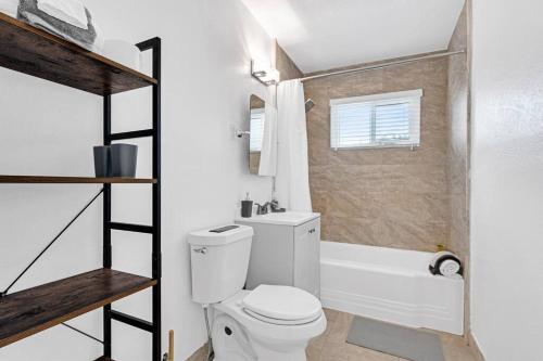 a bathroom with a white toilet and a bath tub at Spacious 5 Bedrooms with Large Pool, 12 minutes to the Ocean in Fort Lauderdale
