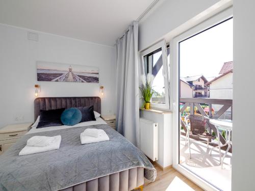a bedroom with a bed and a balcony at PORT 77 in Krynica Morska