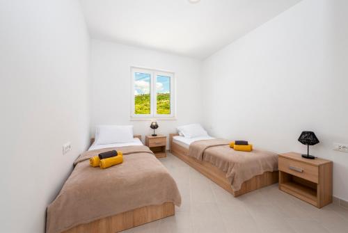 Duas camas num quarto com paredes brancas e uma janela em Villa Vista em Mlini