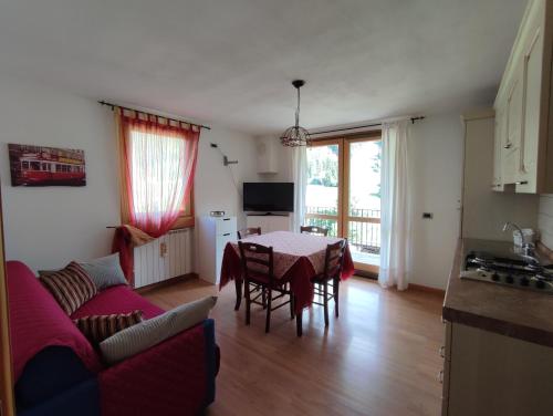 uma sala de estar com uma mesa e um sofá e uma cozinha em Appartamenti Flora Alpina em Temù