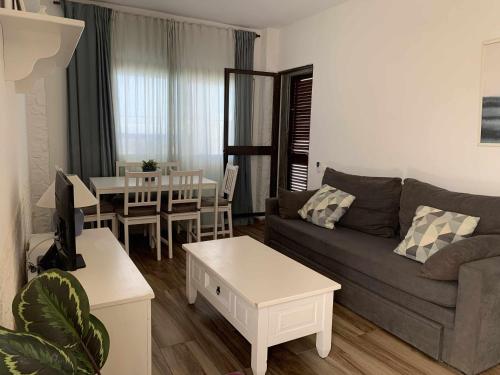 ein Wohnzimmer mit einem Sofa und einem Tisch in der Unterkunft Urb Las Cañas I Apartamento F2 in Tarifa