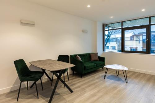 a living room with a table and a green chair at Charles Hope London Brentford in Brentford