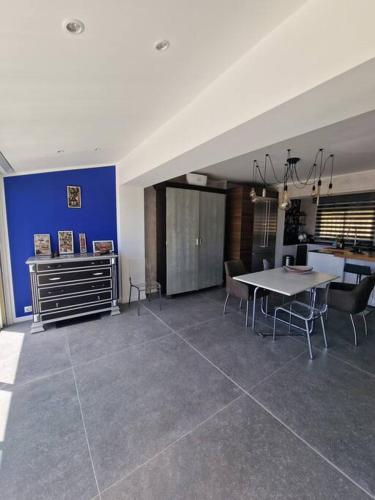 une salle à manger avec une table et un mur bleu dans l'établissement Superbe villa contemporaine vue mer dans résidence avec piscine et tennis, à Hyères