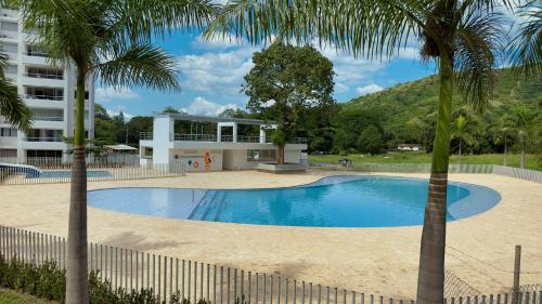 a swimming pool in front of a building with palm trees at Stunning, Brand-new Apartment in Santa Fe de Antioquia