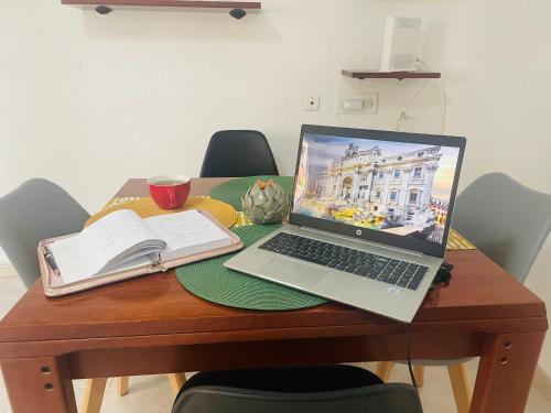 プエルト・デ・サグントにあるCozy 2-Bedroom Serviced Apartment with Netflixの木製テーブルに座って本を読むノートパソコン