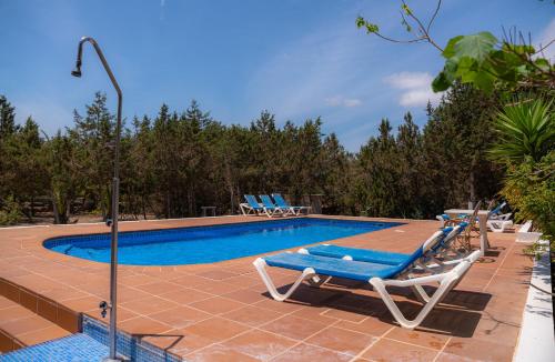 uma piscina com espreguiçadeiras e uma piscina azul em Siamoformentera Villa Beatrice em Es Migjorn