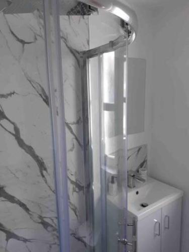 a shower with a glass door next to a sink at The Holiday Hoose in Kinghorn