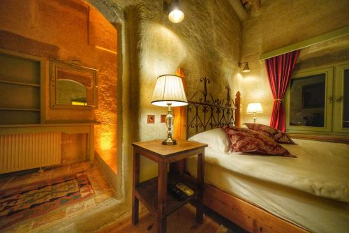 a bedroom with a bed and a lamp on a table at Takaev Cave House in Uchisar