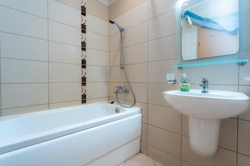 ein Badezimmer mit einem Waschbecken, einer Badewanne und einem Spiegel in der Unterkunft Villa Poesia, Harmony Hills Residence in Rogachevo