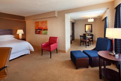 Sheraton Albuquerque Uptown by Marriott في ألباكيركي: غرفة بالفندق سرير وكراسي وطاولة