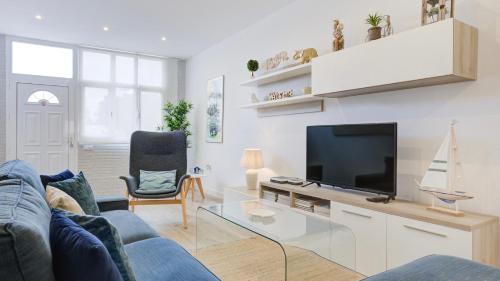 a living room with a blue couch and a tv at Casa MIMAR - moderna, jardín y wifi fibra 1 GB, ideal para vacaciones y teletrabajo in La Oliva