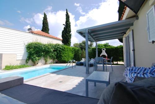 a patio with a pool and a table and chairs at Cypress Garden Villas in Svoronata