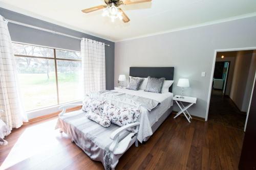 a bedroom with a bed and a large window at LaFleur Guesthouse & Garden Venue in Potchefstroom