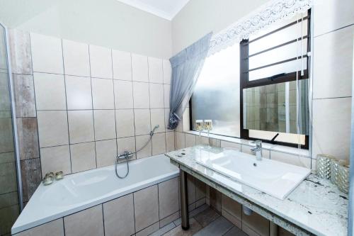 a bathroom with a tub and a sink and a mirror at LaFleur Guesthouse & Garden Venue in Potchefstroom