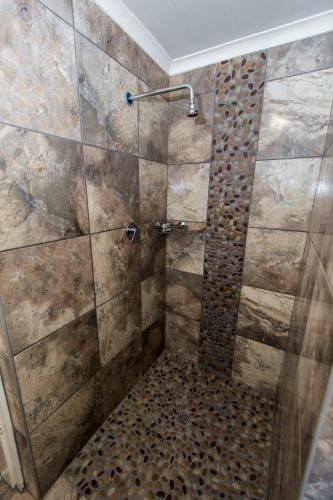 a bathroom with a shower with a stone wall at LaFleur Guesthouse & Garden Venue in Potchefstroom