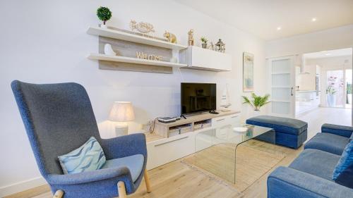 sala de estar con 2 sillas azules y TV en Casa MIMAR - moderna, jardín y wifi fibra 1 GB, ideal para vacaciones y teletrabajo, en La Oliva