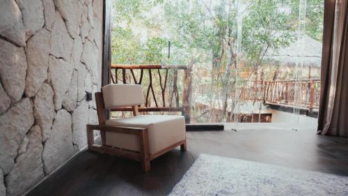 a chair sitting in a room with a large window at Kaaba Luum Jungle Villas in Chemuyil