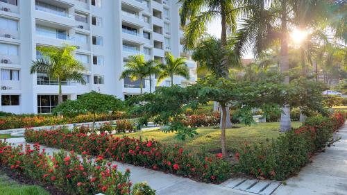 a park in front of a building with flowers and palm trees at Stunning, Brand-new Apartment in Santa Fe de Antioquia