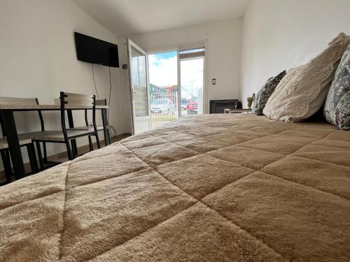 Un dormitorio con una cama grande y una mesa con una mesa. en Bahía Golondrina 2 en Ushuaia