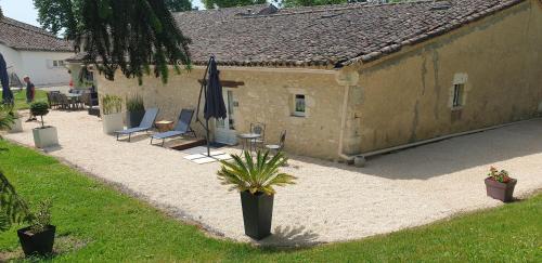 a patio with chairs and an umbrella and a building at Chambre Lily - Au Clos de Parranquet in Parranquet