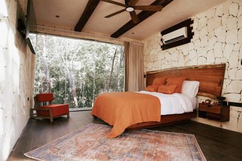 a bedroom with a bed and a large window at Kaaba Luum Jungle Villas in Chemuyil