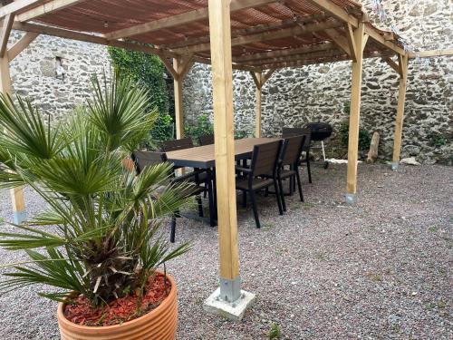 une table et des chaises en bois sous une pergola en bois dans l'établissement Les Limicoles maison proche mer, à Gouville-sur-Mer