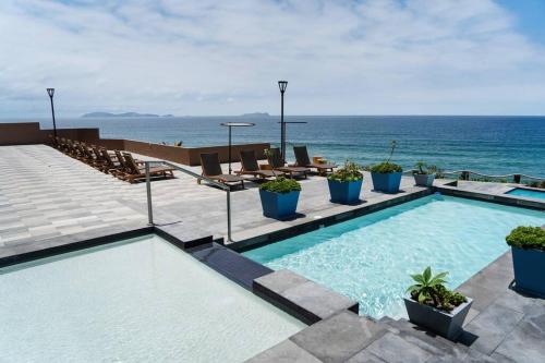 a swimming pool with the ocean in the background at Hotel Suite Luxe Sunset in Tijuana