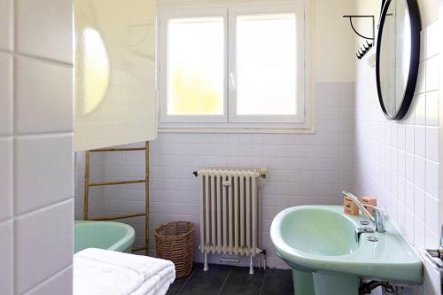 La salle de bains est pourvue d'un lavabo vert et d'une fenêtre. dans l'établissement Ostal périgourdine - Comme à la maison, à Périgueux