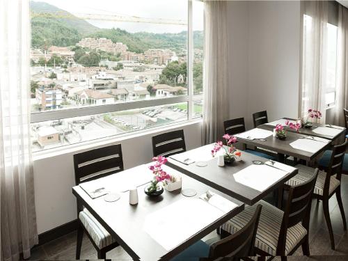 a restaurant with tables and chairs and a large window at Hotel bh Usaquén in Bogotá
