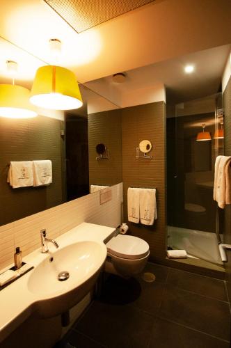 a bathroom with a sink and a toilet and a mirror at Porto Trindade Hotel in Porto