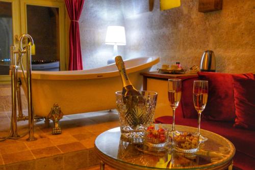 a room with a tub and two glasses of champagne at Takaev Cave House in Uchisar