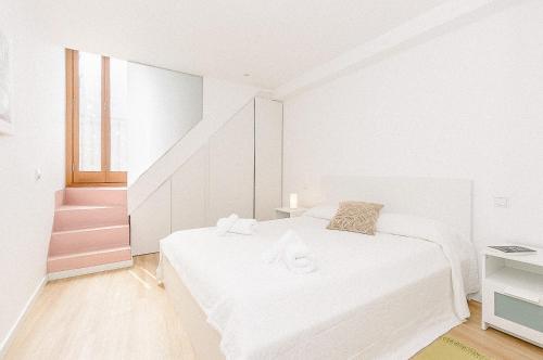 a white bedroom with a bed and a staircase at Townhouse with puig de María view by home villas 360 in Pollença