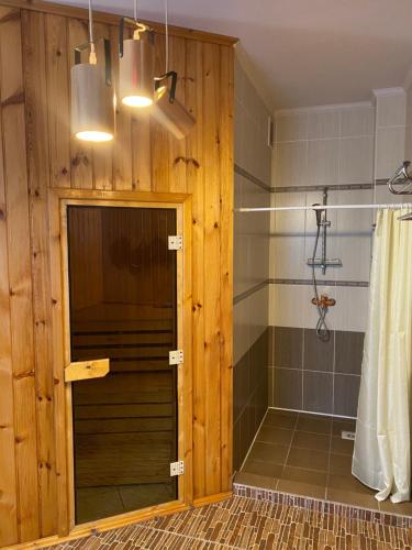 a bathroom with a shower with a wooden wall at Opushka in Vorobʼyëvka